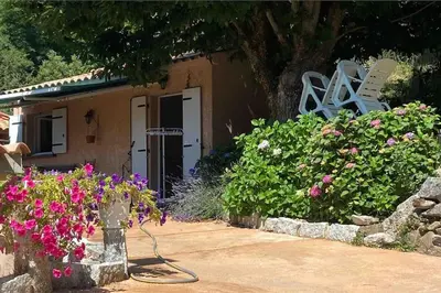 a house with a bunch of flowers in front of it at Mini villa de charme. in Zonza
