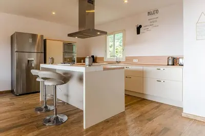 a kitchen with white cabinets and a bar with a stool at Maison vue Mer et Maquis in Olmeto