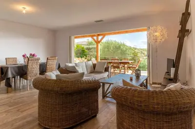 a living room with a couch and chairs and a table at Maison vue Mer et Maquis in Olmeto