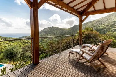 a deck with chairs and a view of the mountains at Maison vue Mer et Maquis in Olmeto