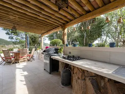 an outdoor kitchen with a stove and a table at Holiday Home Paulka by Interhome in Sainte-Lucie de Porto-Vecchio