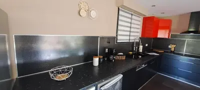 a kitchen with a black counter top and red cabinets at Maison de vacances avec piscine proche mer et montagne in Ghisonaccia