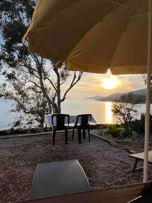 a table and chairs under an umbrella next to the water at Appartement 2 personnes bord de mer in Sagone