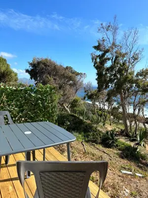 a picnic table and a chair on a deck with the beach at Appartement 2 personnes bord de mer in Sagone