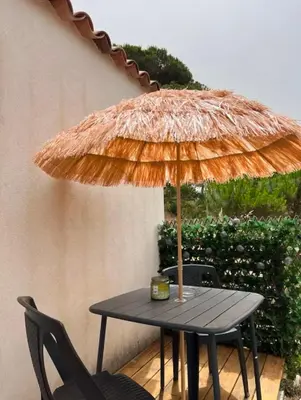 a table with a straw umbrella on a patio at Appartement 2 personnes bord de mer in Sagone
