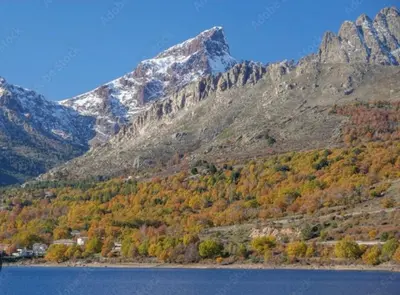 a mountain with fall foliage in front of a lake at À casetta in Albertacce
