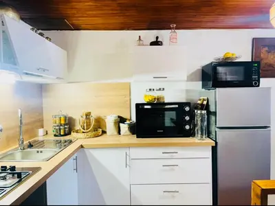 a kitchen with white cabinets and a black microwave at À casetta in Albertacce