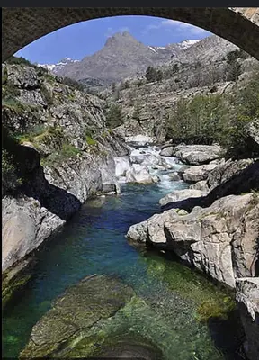 a bridge over a river with a mountain in the background at À casetta in Albertacce