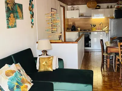 a living room with a green couch and a kitchen at À casetta in Albertacce