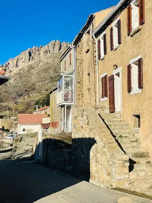 a stone building with a balcony with a mountain in the background at À casetta in Albertacce