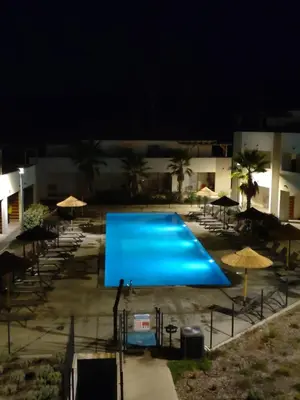 a large blue swimming pool at night with umbrellas at T3 Corse vue mer. pieds dans l'eau N164 in Linguizzetta