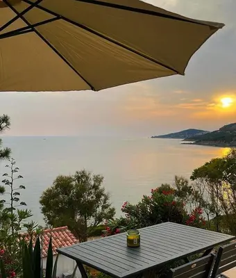 a table with an umbrella and a view of the water at Appartement bord de mer 2 personnes in Sagone