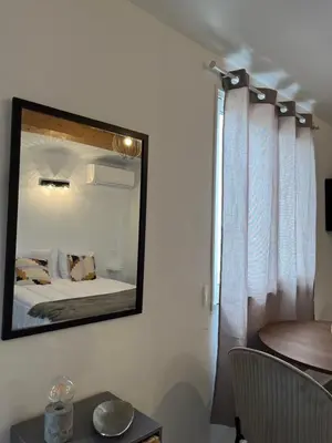 a mirror hanging on a wall next to a bed at Appartement bord de mer 2 personnes in Sagone