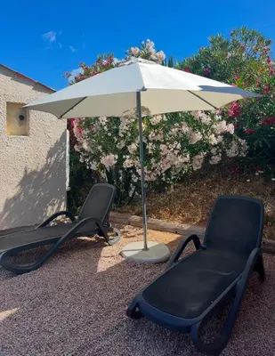 two chairs under an umbrella at Appartement bord de mer 2 personnes in Sagone