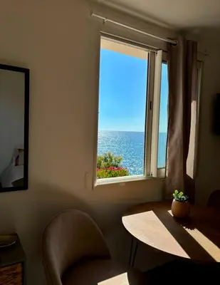 a room with a table and a window with the ocean at Appartement bord de mer 2 personnes in Sagone