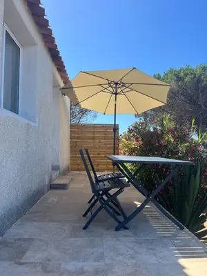 a table with an umbrella and a table and chair at Appartement bord de mer 2 personnes in Sagone