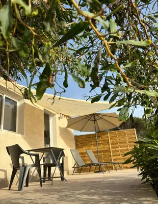 a patio with a table and chairs and an umbrella at Appartement bord de mer 2 personnes in Sagone