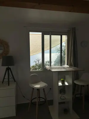 a room with a table and two stools and a window at Appartement bord de mer 2 personnes in Sagone