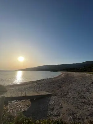 a bench sitting on a beach near the water at Appartement bord de mer 2 personnes in Sagone