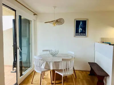 a dining room with a table and white chairs at Appartement T2 vue mer in Porticcio