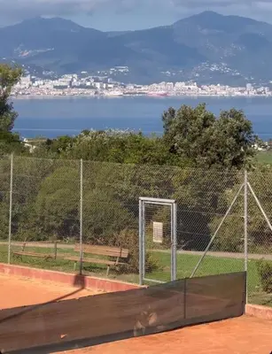 a tennis court with a fence and a bench at Appartement T2 vue mer in Porticcio