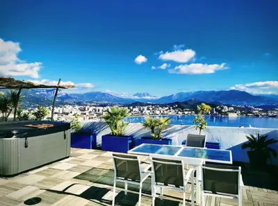 a patio with a view of the water and mountains at Penthouse panoramique avec Jacuzzi in Ajaccio