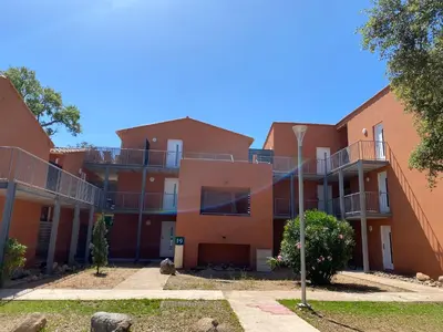 an orange apartment building with balconies and trees at Appartement 2 pièces dans une résidence hôtelière Les Hameaux de Saint-Cyprien in Lecci