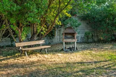 a park bench and a bird house in a yard at Bas de villa, Haute-Corse, vue montagne, 5min des plages in Prunelli-di-Fiumorbo