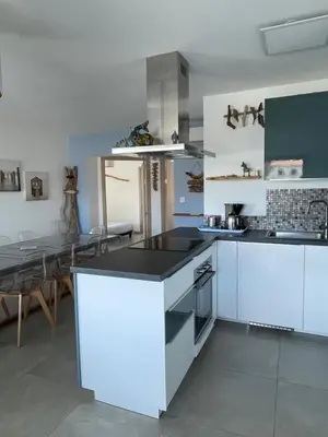 a kitchen with white cabinets and a table in it at Les Toits de Moriani in San-Nicolao