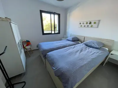 two twin beds in a room with a window at Les Toits de Moriani in San-Nicolao
