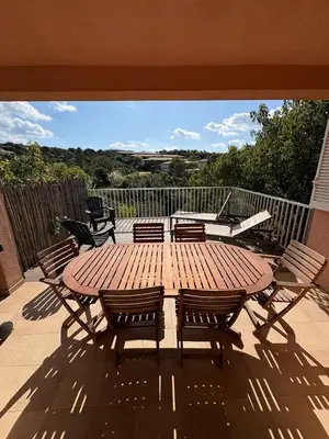 a wooden table and chairs on a patio at Appartement 2 chambres, mezzanine et piscine in Porto-Vecchio