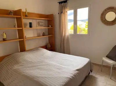 a bedroom with a white bed and a window at Appartement 2 chambres, mezzanine et piscine in Porto-Vecchio
