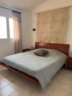a bedroom with a large bed with a wooden headboard at Appartement 2 chambres, mezzanine et piscine in Porto-Vecchio