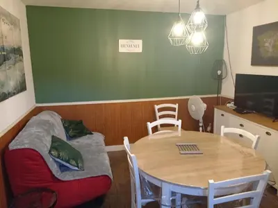 a dining room with a table and a couch and a desk at Ravissant appartement au cœur de Piana in Piana