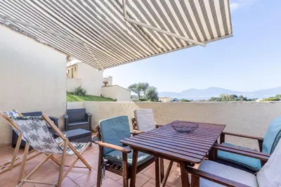 a patio with a wooden table and chairs at Azura Prugna - Maison avec piscine partagée in Grosseto-Prugna
