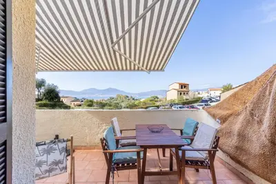 a patio with a table and chairs on a balcony at Azura Prugna - Maison avec piscine partagée in Grosseto-Prugna