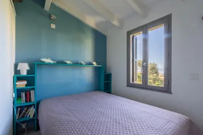 a bedroom with a blue bed and a window at Azura Prugna - Maison avec piscine partagée in Grosseto-Prugna