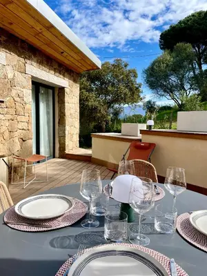 a table with plates and wine glasses on a patio at Caseddu 100m de la plage in Belvédère