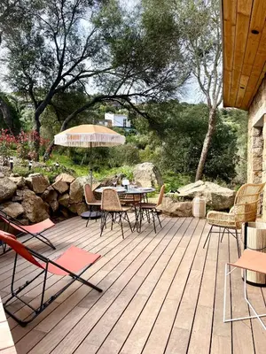 a wooden deck with chairs and a table and an umbrella at Caseddu 100m de la plage in Belvédère