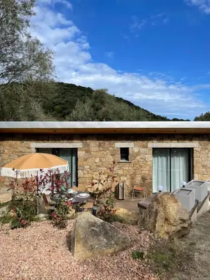 a stone house with a patio and an umbrella at Caseddu 100m de la plage in Belvédère