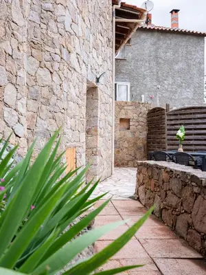 a stone building with a stone wall and a patio at Appartement départ GR20 in Calenzana