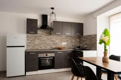 a kitchen with a table and a white refrigerator at Appartement départ GR20 in Calenzana
