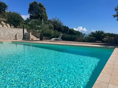 a blue swimming pool with a chair in the background at Studio 1 avec piscine & vue sur la baie d'Ajaccio in Alata