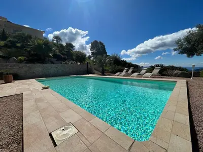 a swimming pool with blue water in a yard at Studio 1 avec piscine & vue sur la baie d'Ajaccio in Alata