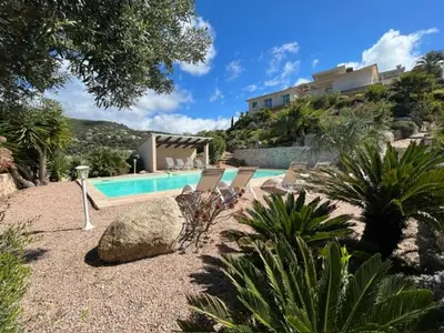 a swimming pool with two chairs and a house at Studio 1 avec piscine & vue sur la baie d'Ajaccio in Alata
