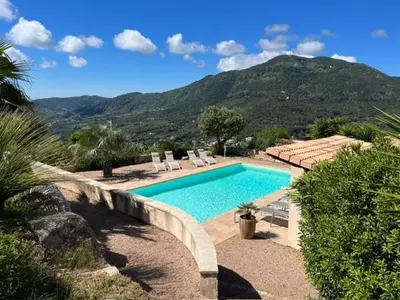 a swimming pool with chairs and a mountain in the background at Studio 1 avec piscine & vue sur la baie d'Ajaccio in Alata