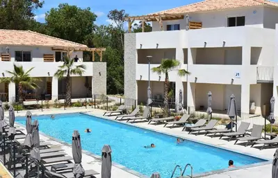 a swimming pool in front of a hotel with lounge chairs at T2 VUE MER CORSE N193 in Linguizzetta