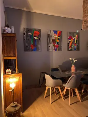 a dining room with a table and four paintings on the wall at T2 Paisible et cosy in Sollacaro
