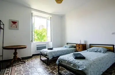 a bedroom with two beds and a table and a window at Casamea - Famille, 2 chambres, Centre , Calme in Ajaccio