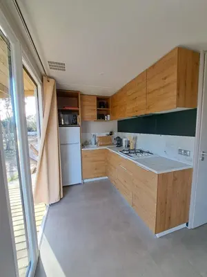 a kitchen with wooden cabinets and a white refrigerator at Chalet n * 1 au cœur du maquis in Bonifacio